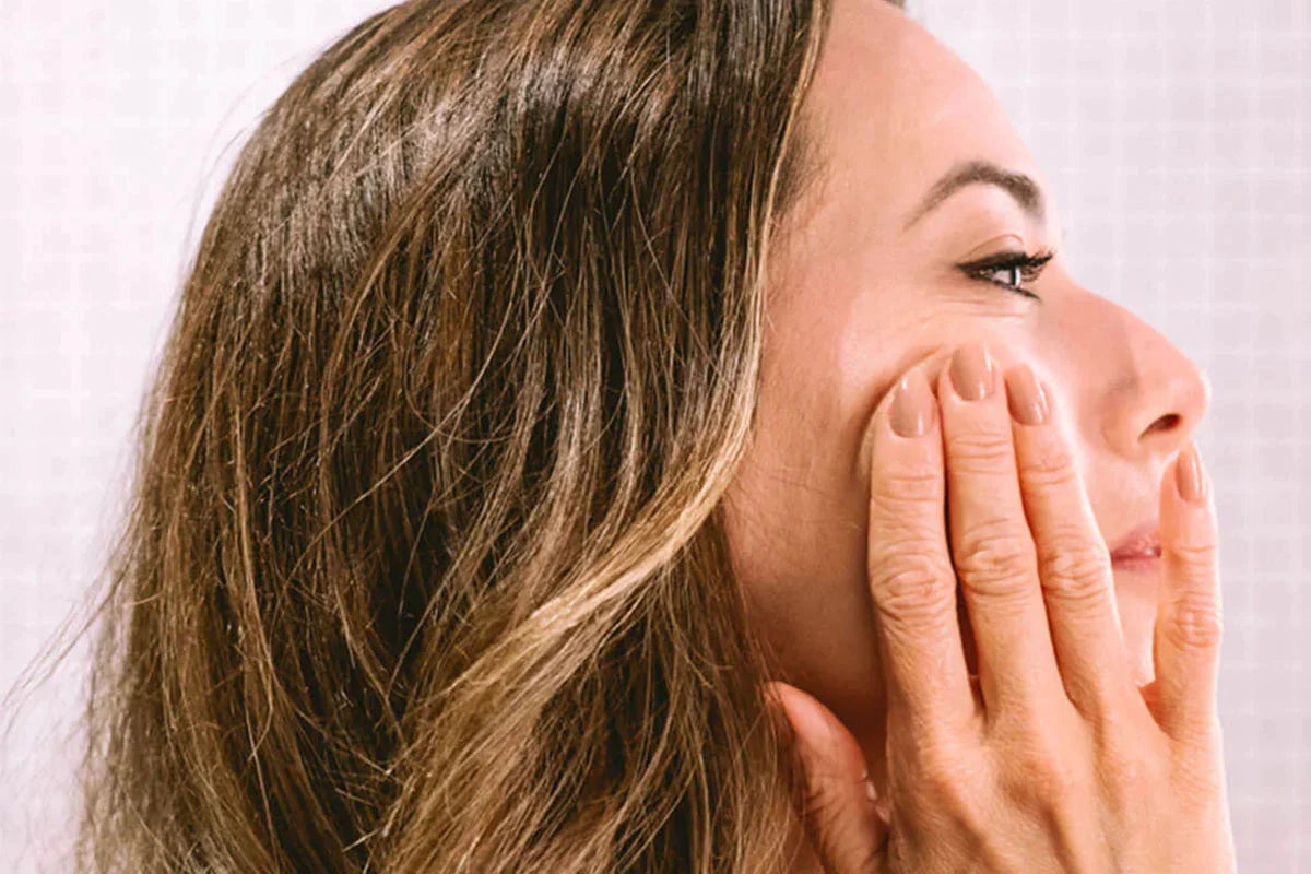 Eine Frau reibt sich die Anti-Aging Creme – CBD & Retinol in ihr Gesicht.