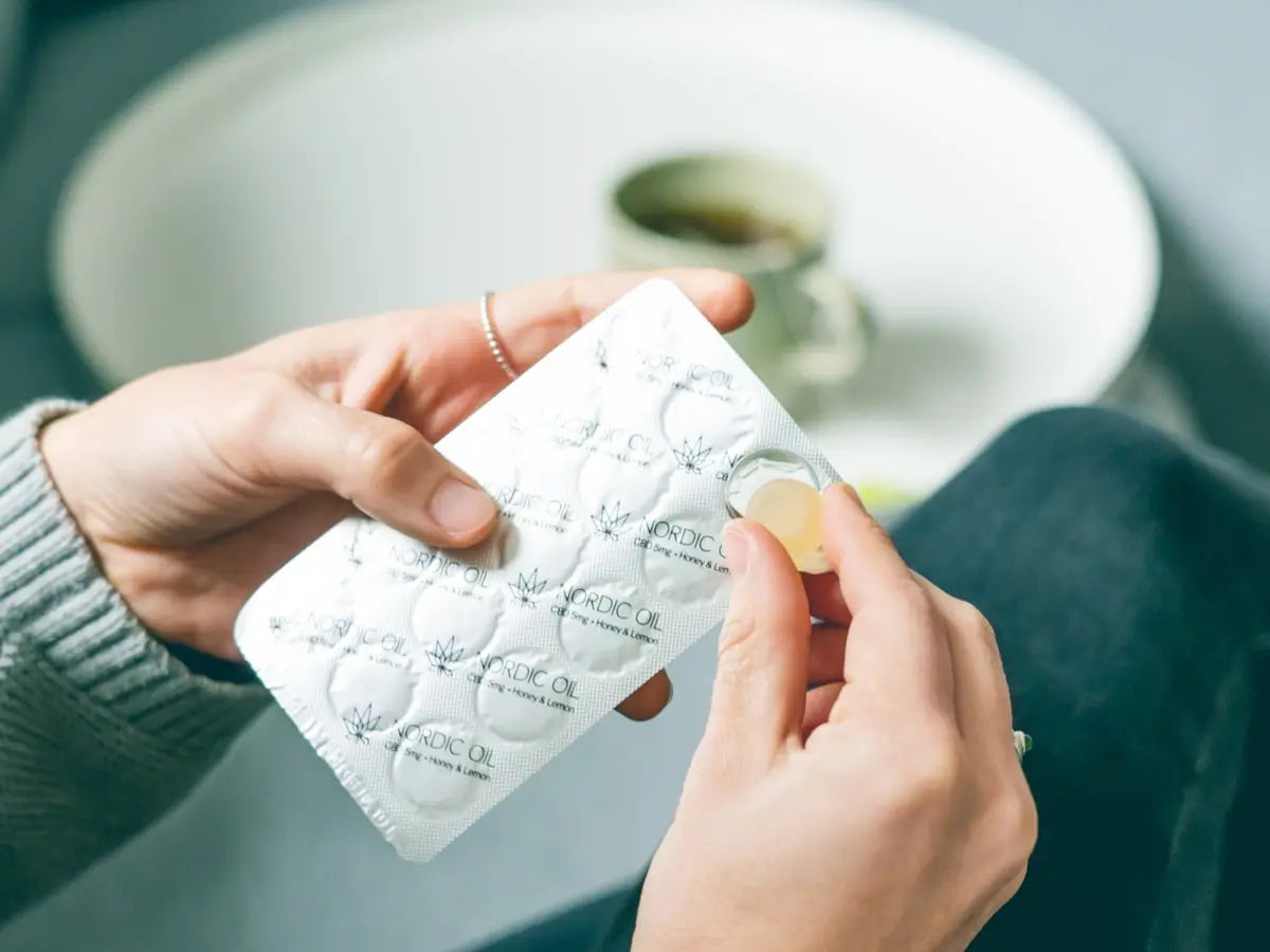 Eine Frau nimmt eine CBD Lutschtablette aus der Blisterpackeung