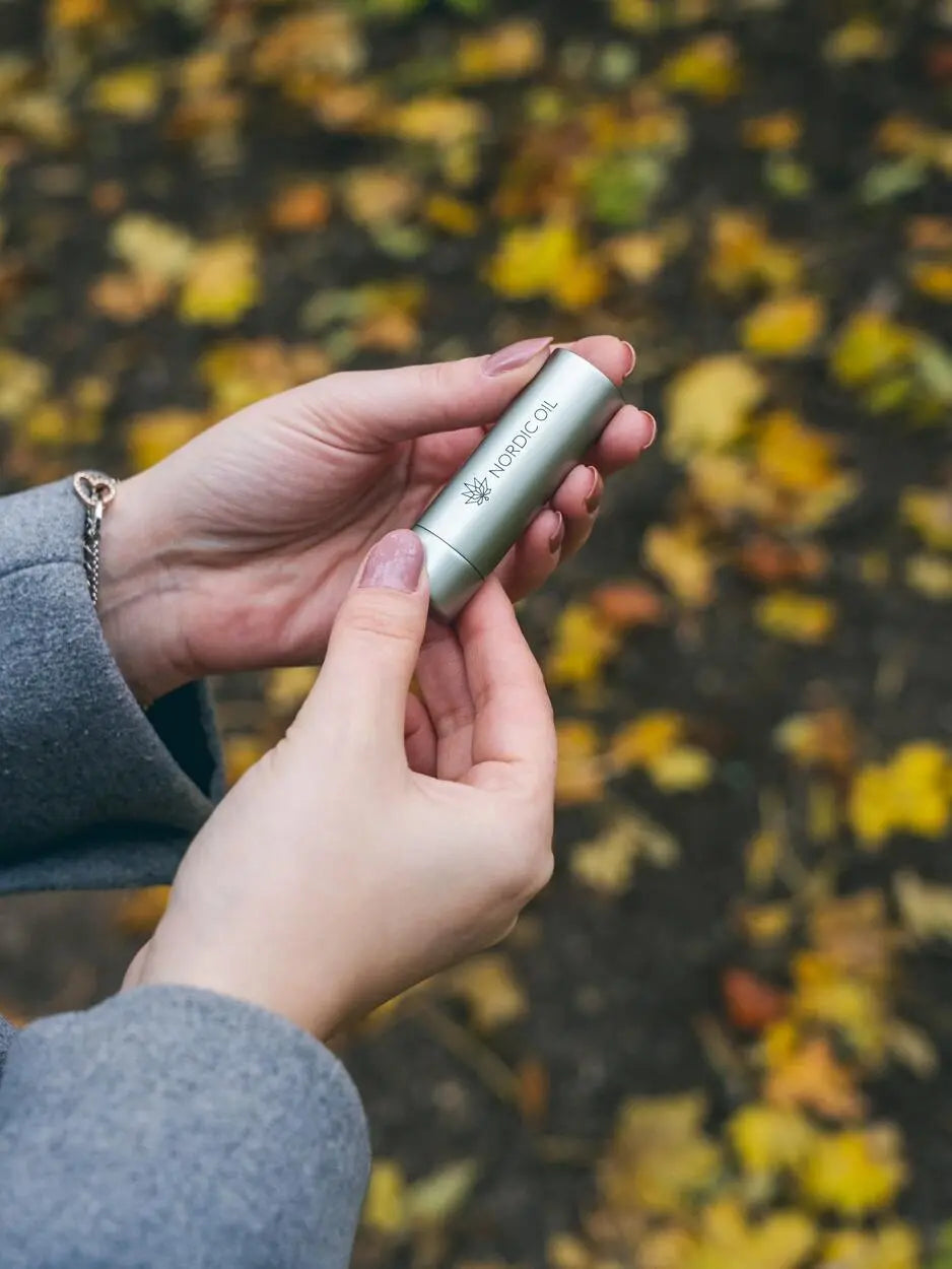 Eine Frau öffnet eine Packung von Nordic Oil, die CBD Lippenpflege enthält