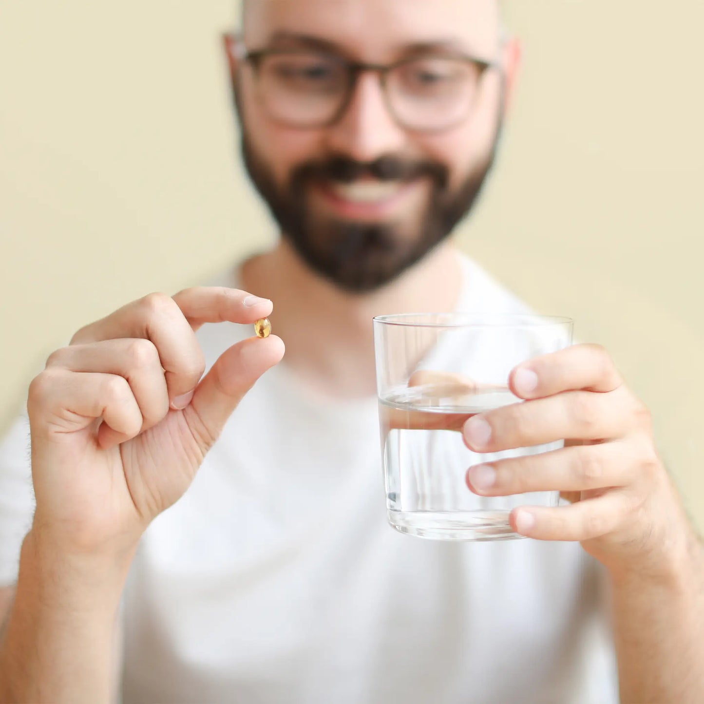 Mann hält Softgel und ein Glas Wasser in den Händen