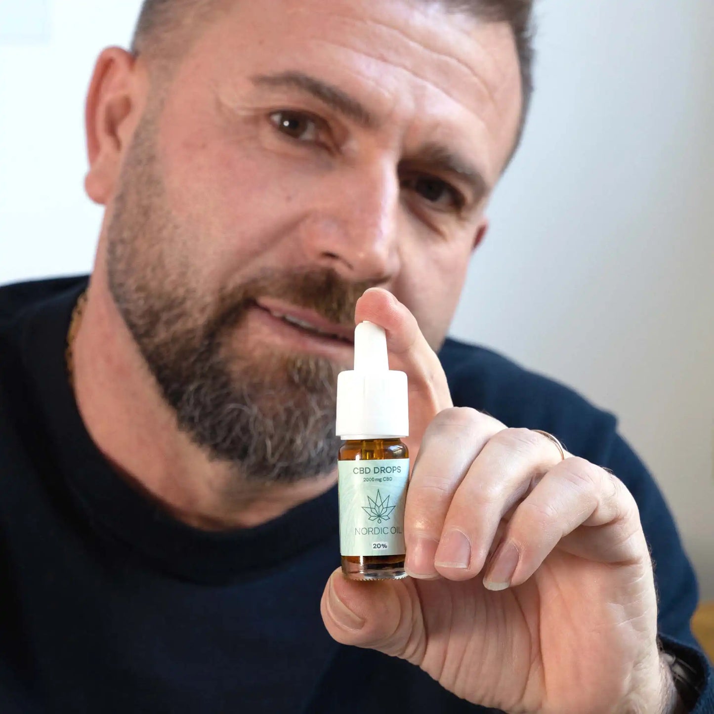 Ein Mann hält eine Flasche 20% CBD Öl Plus von Nordic Oil