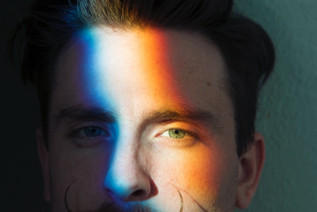 Einem Mann scheint ein Regenbogen ins Gesicht.
