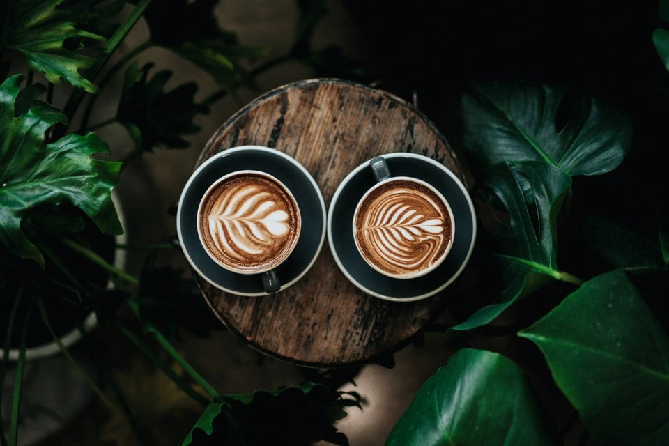 Zwei Tassen Kaffe stehen auf einem Holztisch.