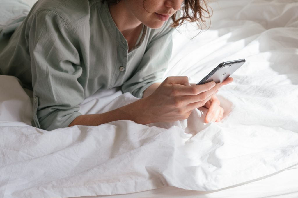 Frau auf dem Bett am Handy