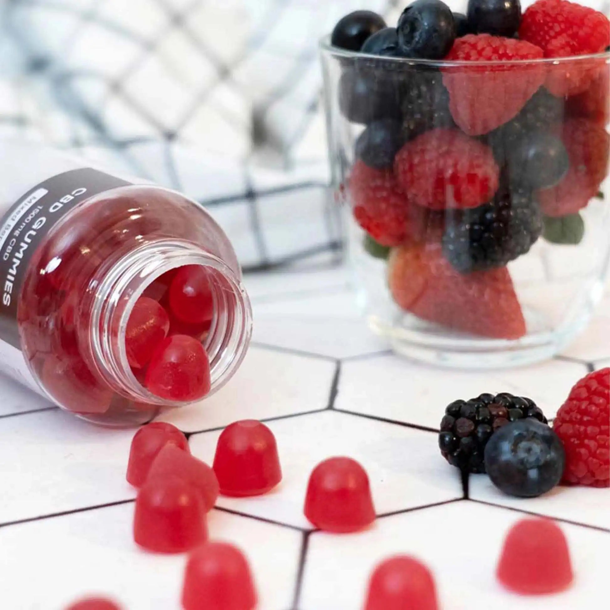 Fruchtgummi Packung liegt ausgeschüttet da und ein Glas Beeren steht daneben