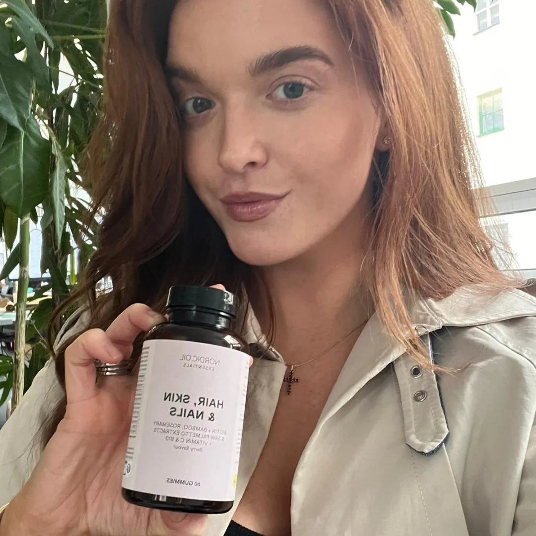 Frau hält Nordic Oil Haar-, Haut- und Nägel-Nahrungsergänzung in einer schwarzen Flasche