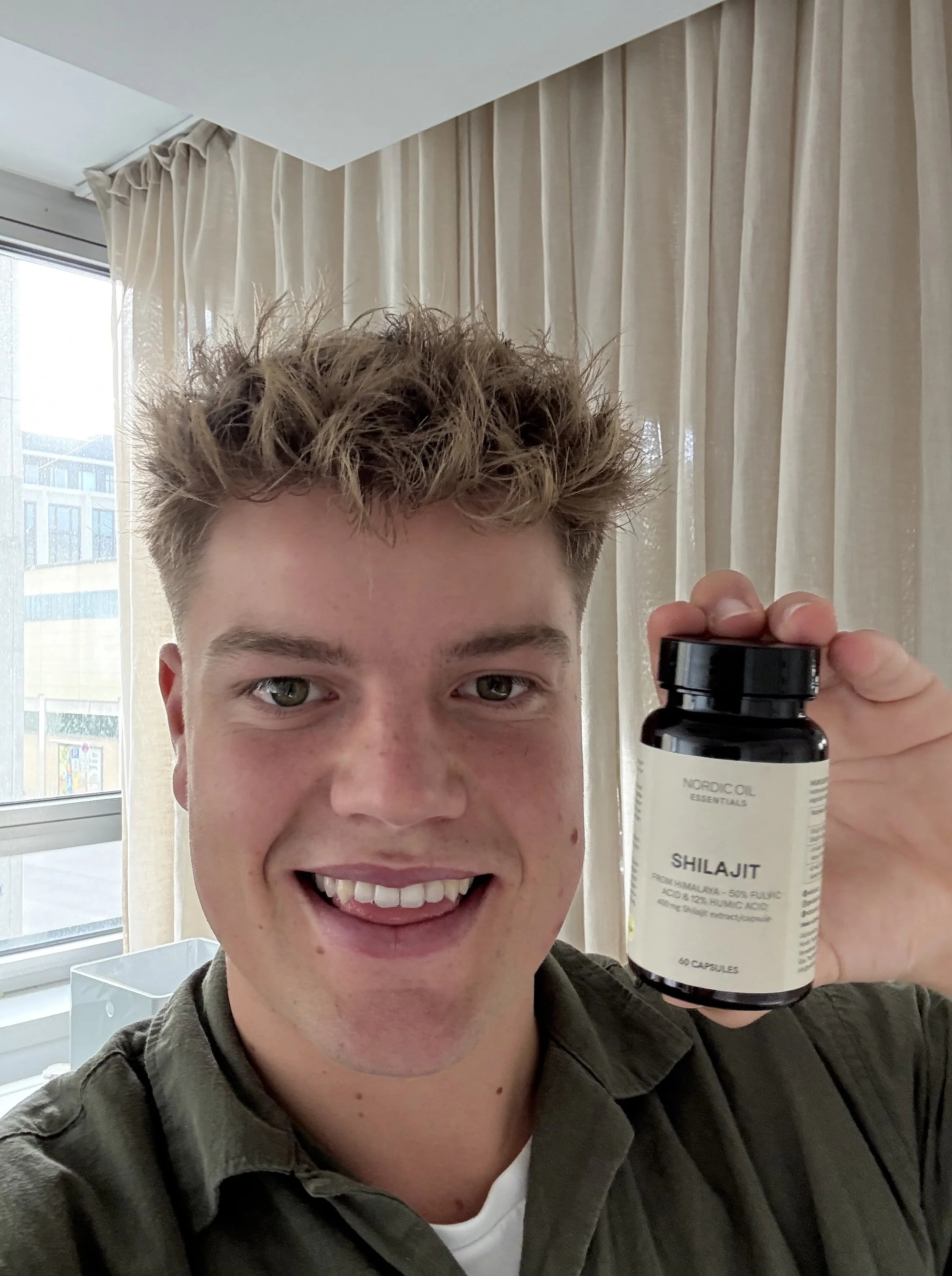 Junger Mann hält eine Dose Nordic Oil Essentials Shilajit-Kapseln.