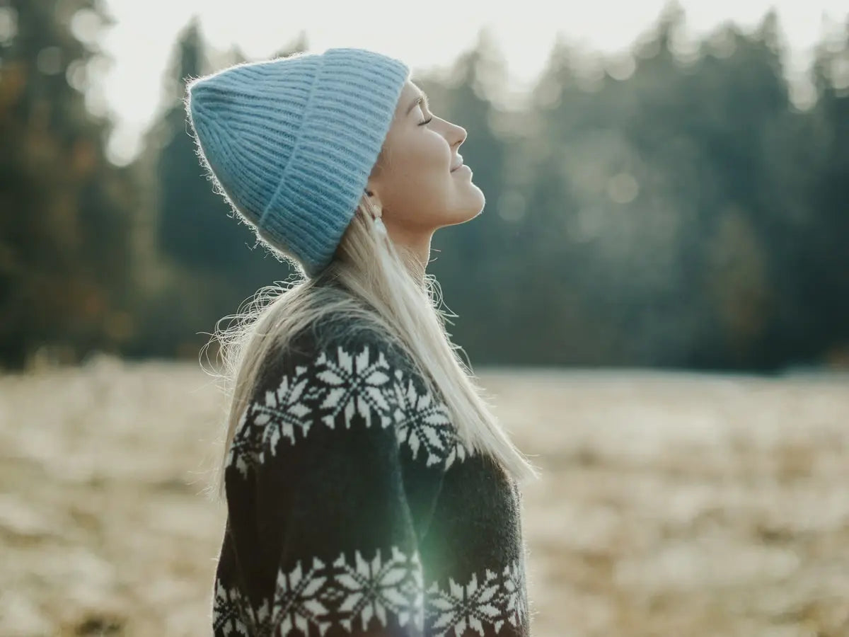 Frau mit Mütze im Freien genießt die Natur, nachdem sie CBD von Nordic Oil verwendet hat