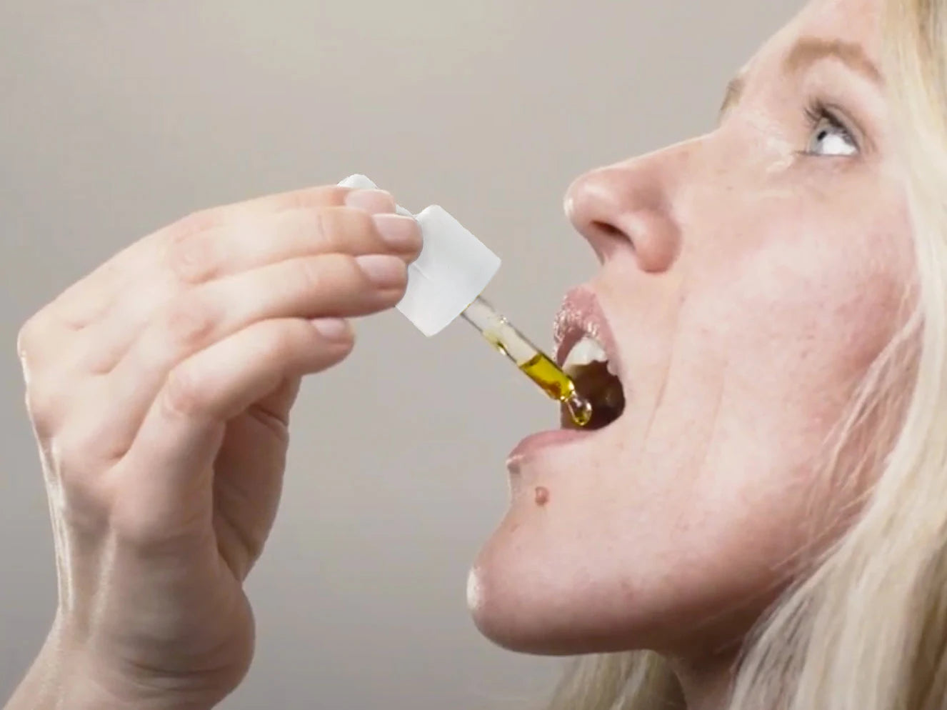 Eine Frau tropft sich CBD Öl (10%) in den Mund.