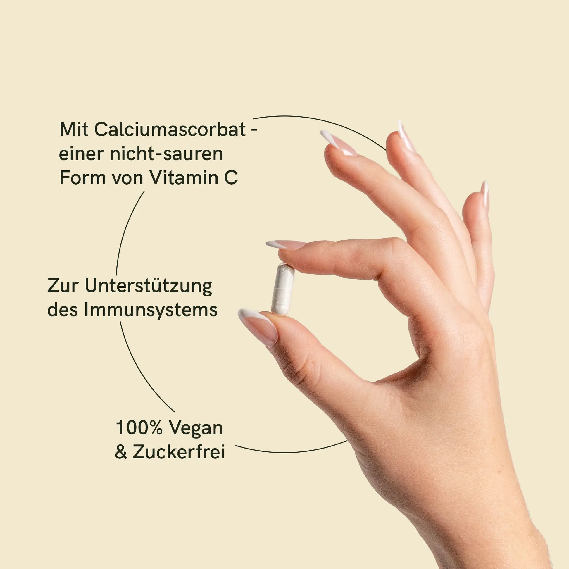 Eine Hand hält eine Vitamin C Kapsel mit Information: Mit Calciumascorbat einer nicht-sauren Form von Vitamin C; Zur Unterstützung des Immunsystems; 100% Vegan & Zuckerfrei 