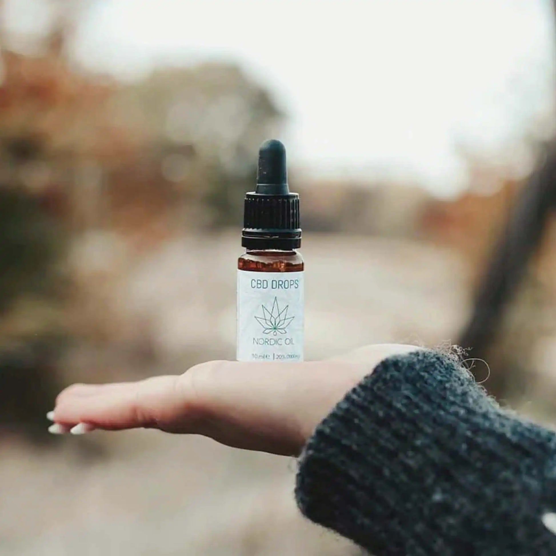 Eine Frau hält eine Flasche CBD Öl 20% in der flachen Hand