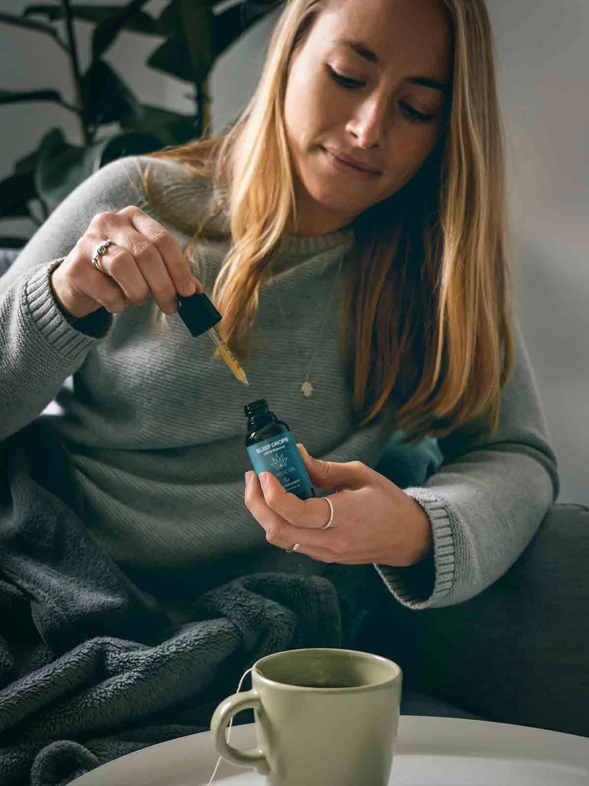 Eine Frau tropft sich CBD Mani Drops + Melatonin in ihren Tee