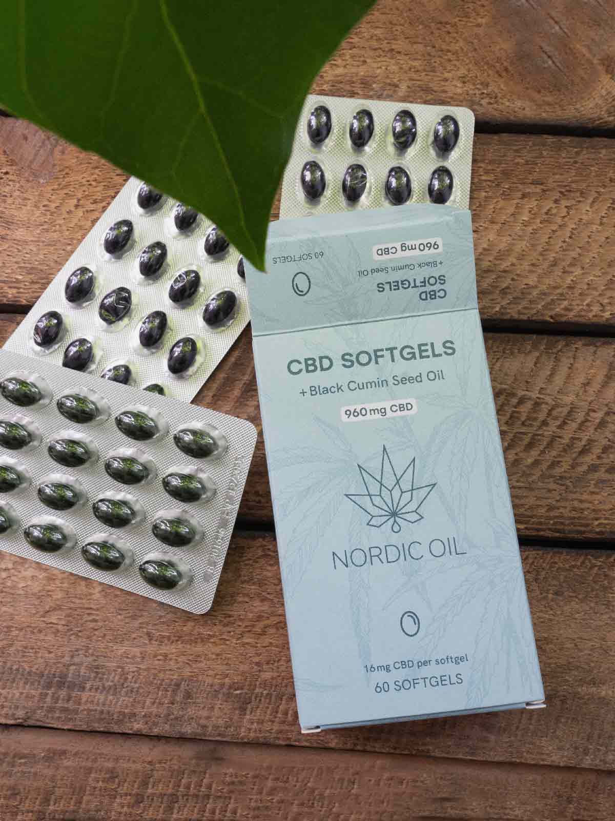 Eine Packung des CBD Kapseln (960mg) liegt offen auf einem Holztisch. 